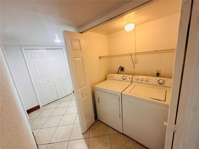 laundry area featuring a textured ceiling, light tile patterned floors, and separate washer and dryer