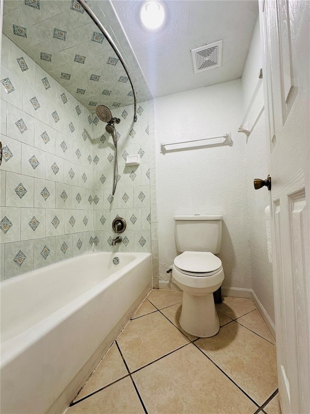 bathroom with tile patterned flooring, toilet, and tiled shower / bath