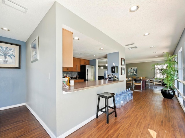 kitchen with stainless steel refrigerator, a textured ceiling, and wood-type flooring