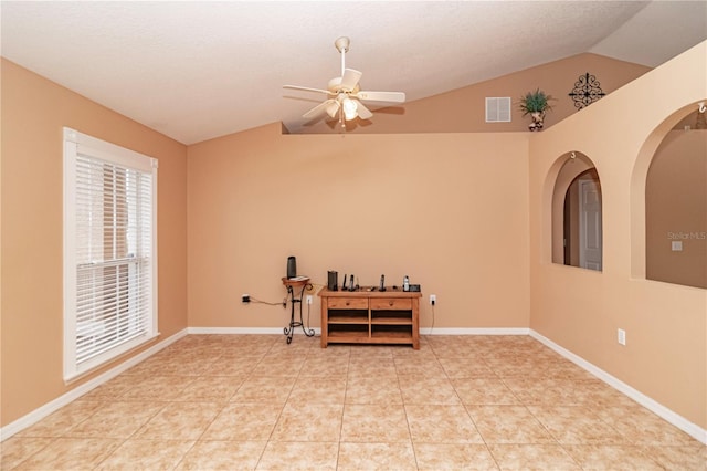 tiled empty room with a textured ceiling, ceiling fan, and vaulted ceiling