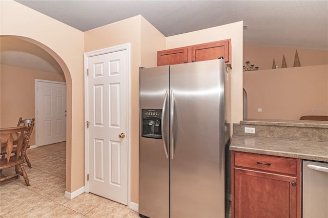 kitchen with stainless steel appliances, light tile patterned floors, and vaulted ceiling