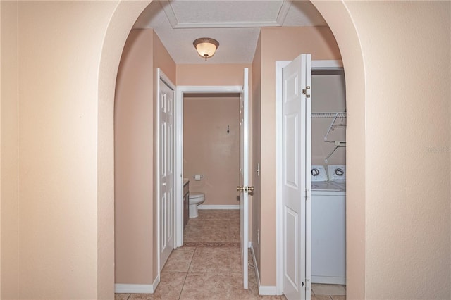 corridor with independent washer and dryer and light tile patterned floors