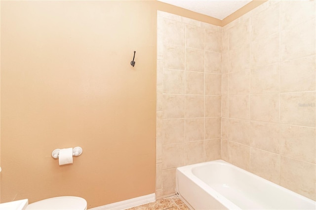 bathroom with tiled shower / bath, tile patterned floors, and toilet