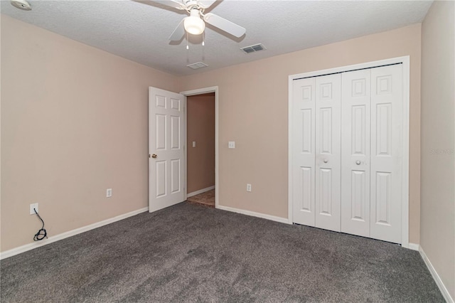 unfurnished bedroom with a closet, a textured ceiling, dark carpet, and ceiling fan