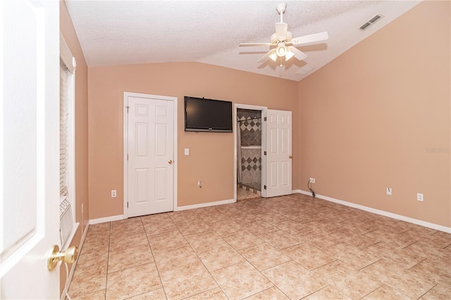 unfurnished bedroom with a spacious closet, a textured ceiling, light tile patterned floors, vaulted ceiling, and ceiling fan