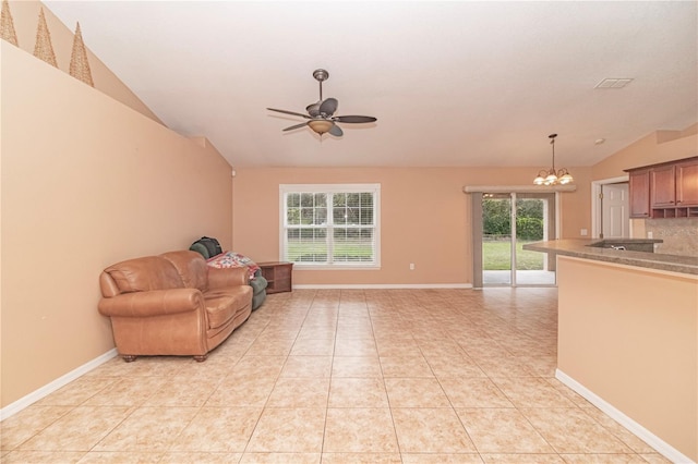 living room featuring vaulted ceiling, light tile patterned flooring, and ceiling fan with notable chandelier