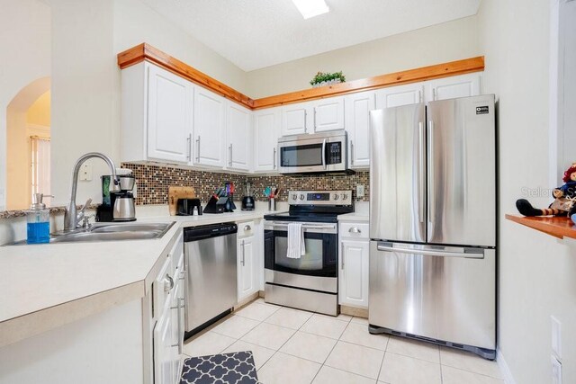 8447 Crystal Cove Loop, Kissimmee, FL 34747 - kitchen with stainless steel appliances, a sink, arched walkways, light countertops, and white cabinetry