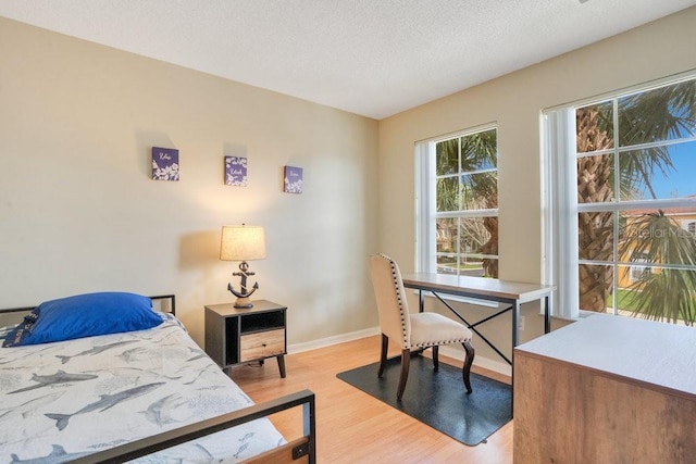 bedroom featuring a textured ceiling and light hardwood / wood-style flooring