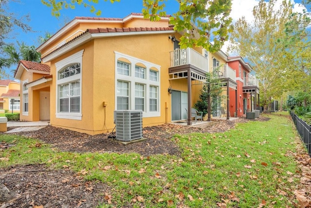 back of property featuring a lawn, a balcony, and central AC