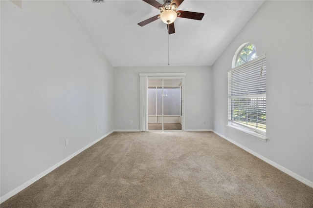 carpeted empty room featuring ceiling fan, vaulted ceiling, and a healthy amount of sunlight