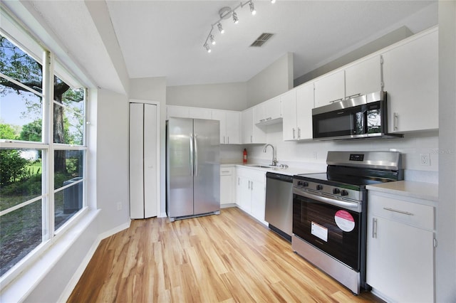 kitchen with stainless steel appliances, light wood-type flooring, white cabinetry, sink, and lofted ceiling