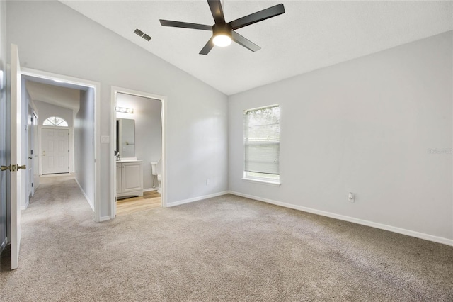 unfurnished bedroom featuring connected bathroom, lofted ceiling, ceiling fan, and carpet floors