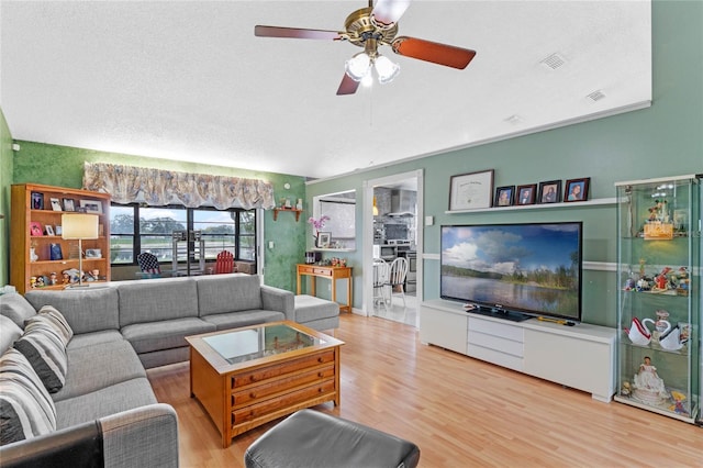 living room with a textured ceiling, wood-type flooring, and ceiling fan