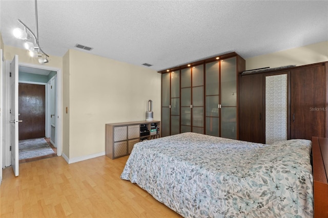 bedroom with light wood-type flooring and a textured ceiling