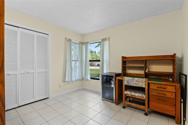 bedroom featuring light tile patterned flooring, a textured ceiling, a closet, and wine cooler