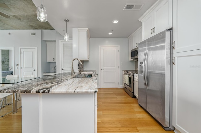 kitchen featuring light hardwood / wood-style floors, stainless steel appliances, sink, white cabinetry, and decorative light fixtures