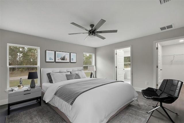 bedroom with a spacious closet, ceiling fan, ensuite bathroom, and a closet