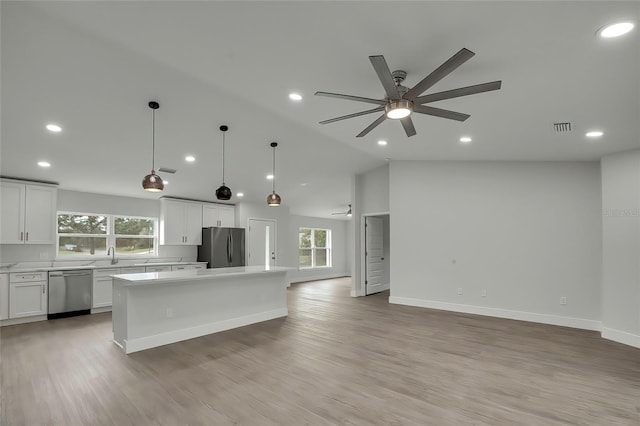 kitchen with white cabinetry, a center island, decorative light fixtures, vaulted ceiling, and appliances with stainless steel finishes