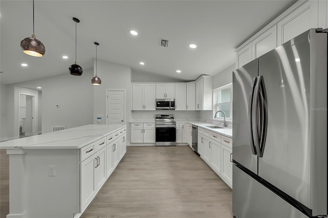 kitchen with light stone countertops, stainless steel appliances, white cabinets, hanging light fixtures, and lofted ceiling