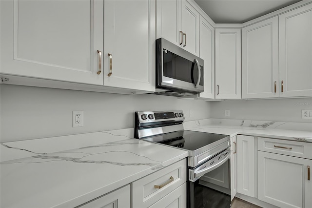 kitchen with light stone counters, white cabinets, and appliances with stainless steel finishes