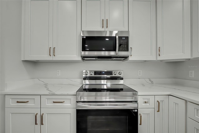 kitchen with white cabinetry, light stone counters, and appliances with stainless steel finishes