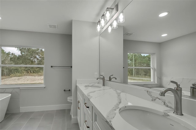 bathroom with tile patterned flooring, vanity, a tub to relax in, and toilet