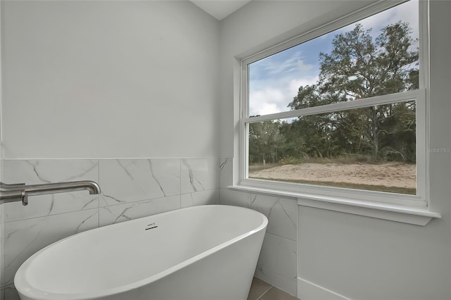 bathroom featuring a bath and tile walls