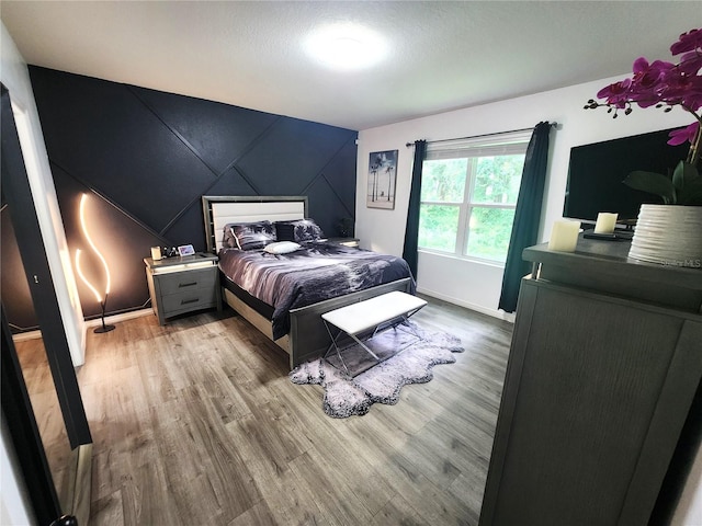 bedroom featuring vaulted ceiling, hardwood / wood-style flooring, and a textured ceiling