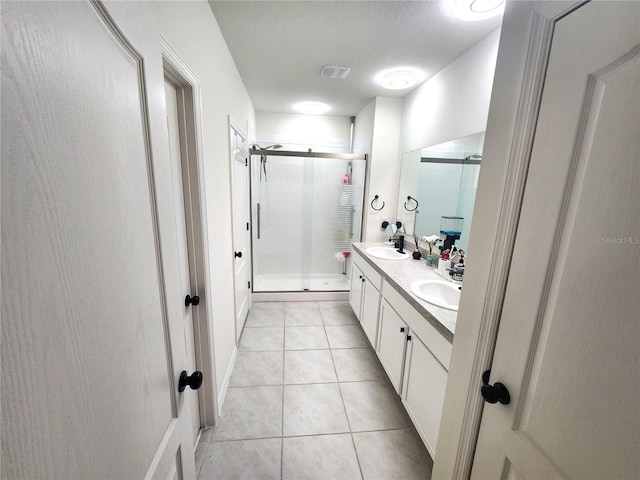 bathroom featuring walk in shower, vanity, a textured ceiling, and tile patterned floors