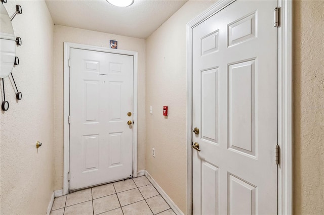 doorway to outside featuring light tile patterned floors and a textured ceiling