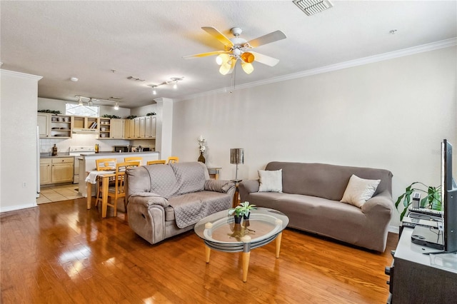 living room with a textured ceiling, light hardwood / wood-style floors, ceiling fan, and ornamental molding