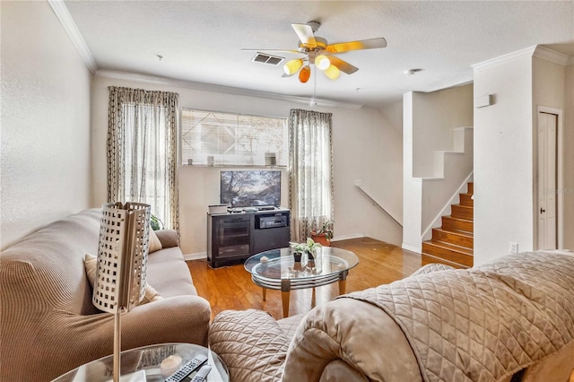 living room with a textured ceiling, light hardwood / wood-style floors, ceiling fan, and crown molding