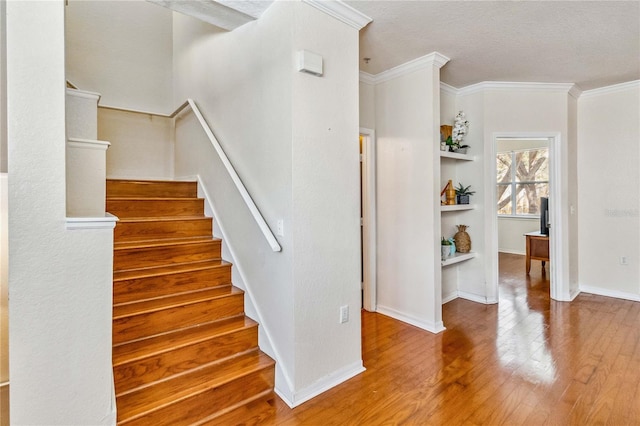 stairs featuring crown molding, a textured ceiling, and hardwood / wood-style flooring