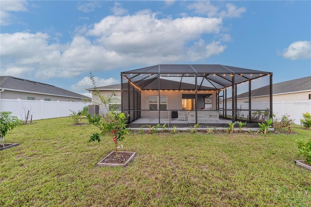 rear view of house with glass enclosure, a patio, and a yard