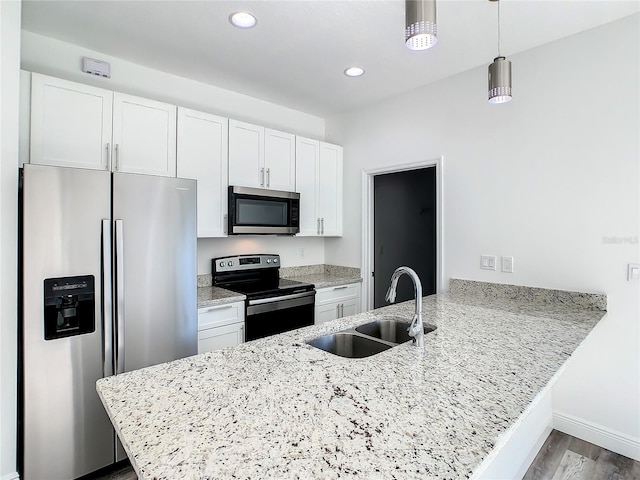 kitchen featuring sink, kitchen peninsula, appliances with stainless steel finishes, decorative light fixtures, and white cabinets