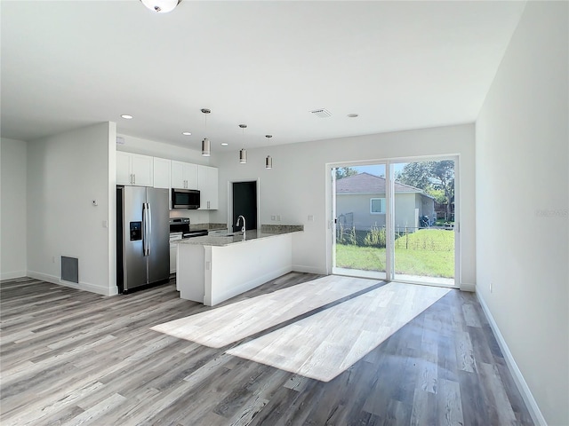 kitchen featuring light hardwood / wood-style floors, hanging light fixtures, stone countertops, white cabinetry, and appliances with stainless steel finishes