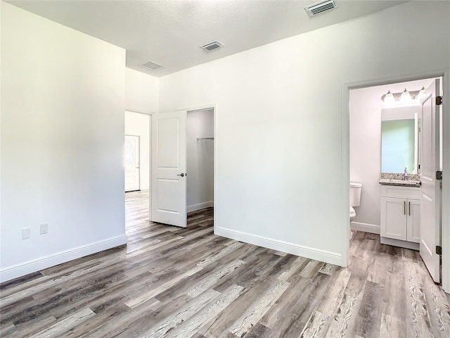 unfurnished bedroom featuring light wood-type flooring, sink, and ensuite bathroom