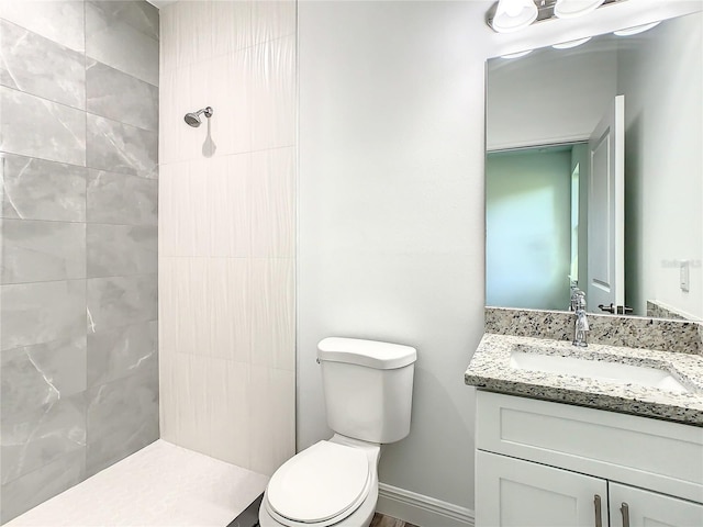 bathroom featuring toilet, vanity, and a tile shower