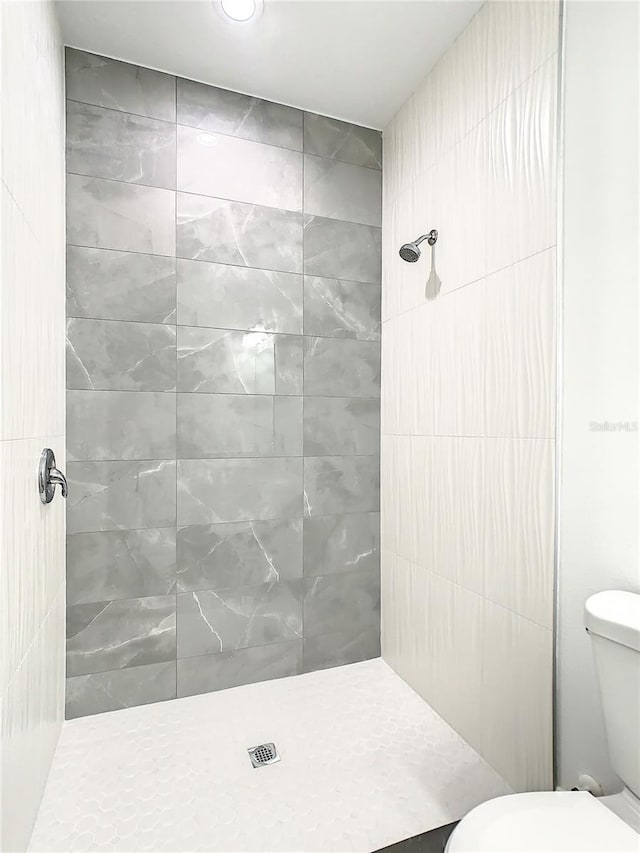 bathroom featuring tiled shower and toilet