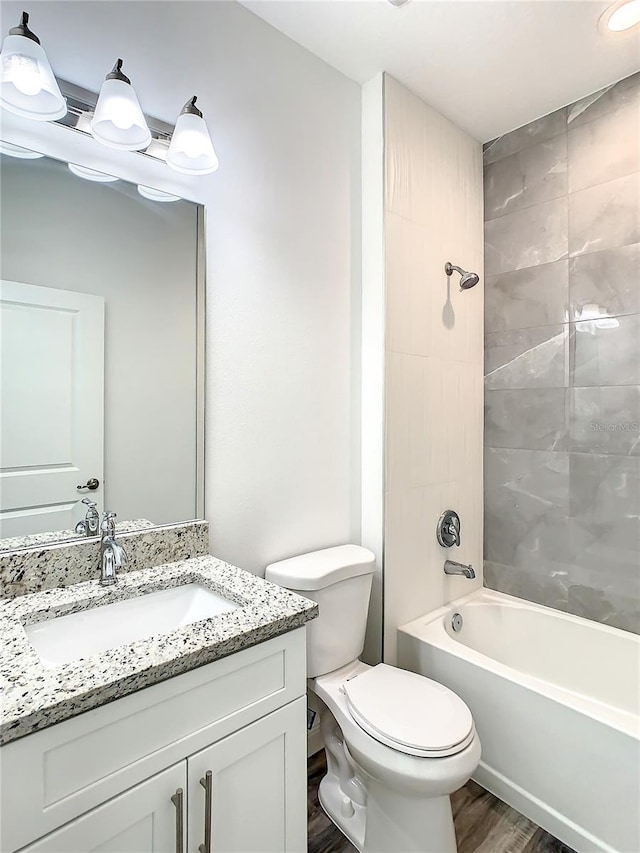 full bathroom with wood-type flooring, toilet, vanity, and tiled shower / bath