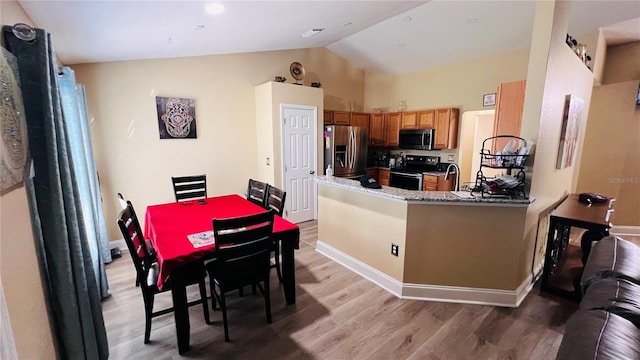 kitchen featuring kitchen peninsula, light hardwood / wood-style flooring, lofted ceiling, and appliances with stainless steel finishes