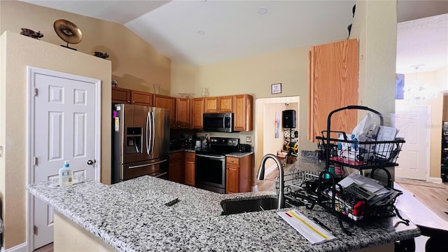 kitchen featuring kitchen peninsula, appliances with stainless steel finishes, vaulted ceiling, and sink