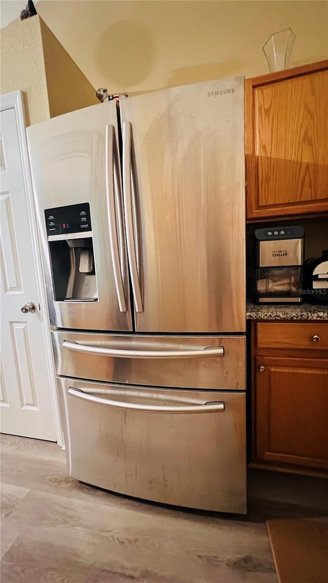 kitchen featuring stainless steel fridge with ice dispenser and light hardwood / wood-style flooring