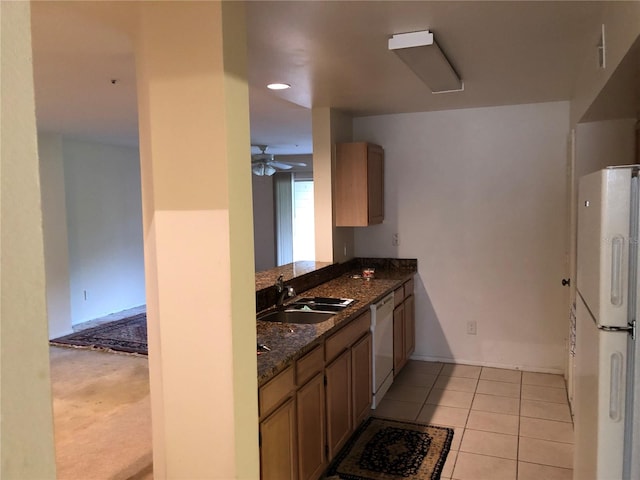 kitchen featuring ceiling fan, sink, white appliances, light tile patterned floors, and dark stone counters