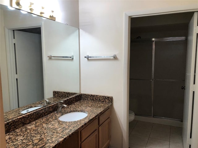 bathroom with a shower with shower door, tile patterned floors, vanity, and toilet