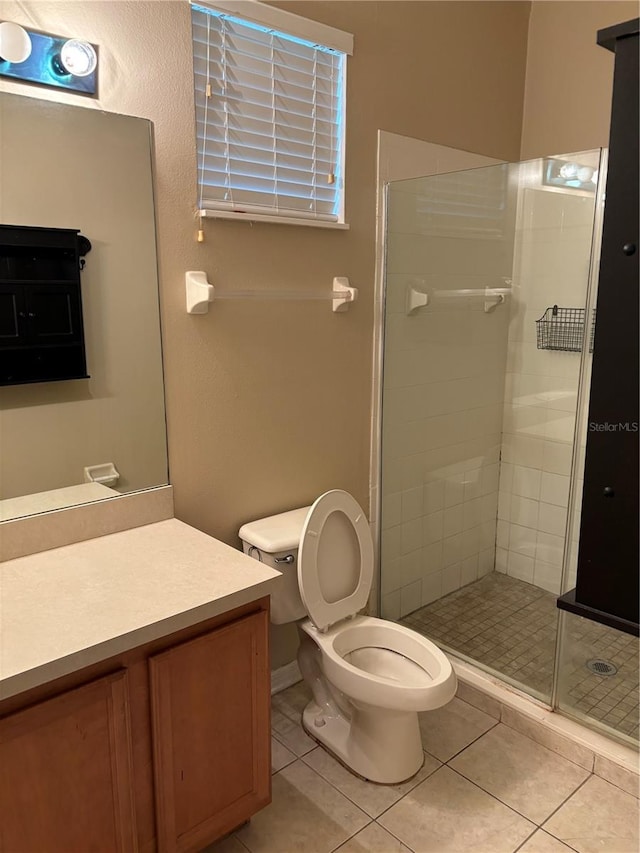 bathroom featuring tile patterned floors, vanity, toilet, and an enclosed shower