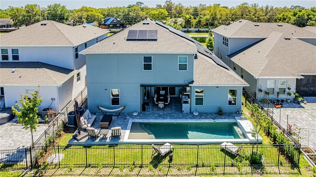 back of house featuring a fenced in pool, a patio area, outdoor lounge area, a yard, and solar panels