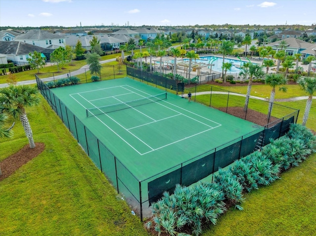 view of tennis court with a yard and a community pool