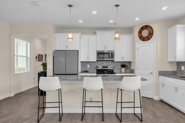 kitchen with appliances with stainless steel finishes, light hardwood / wood-style floors, a kitchen island, and pendant lighting