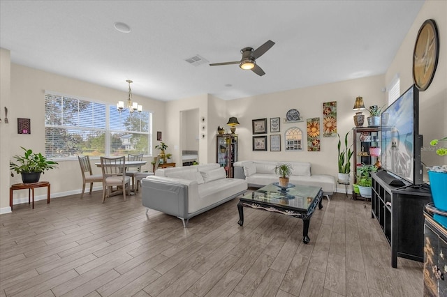 living room featuring ceiling fan with notable chandelier and light hardwood / wood-style flooring